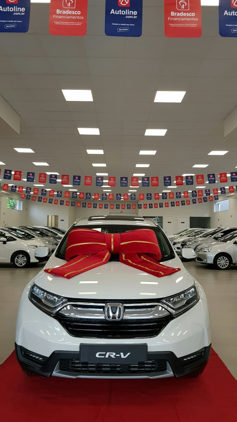 Nuova Honda CR-V bianca con fiocco rosso su tappeto rosso.